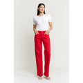 Woman wearing a white top and red pants on a plain background